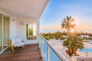 Luxury condo balcony overlooking sunset on ocean, palm trees